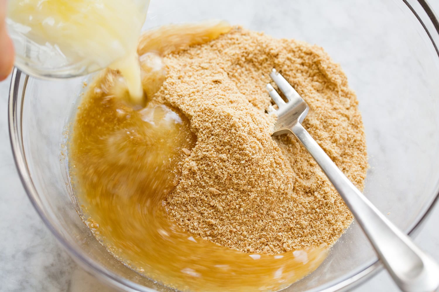 Graham cracker crumbs with melted butter being added.