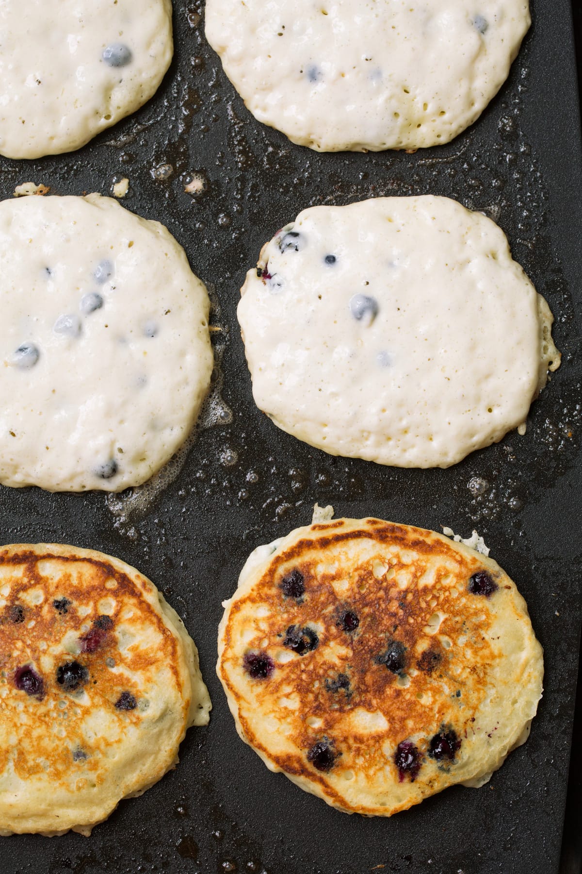 Showing how to cook blueberry pancakes on a griddle.