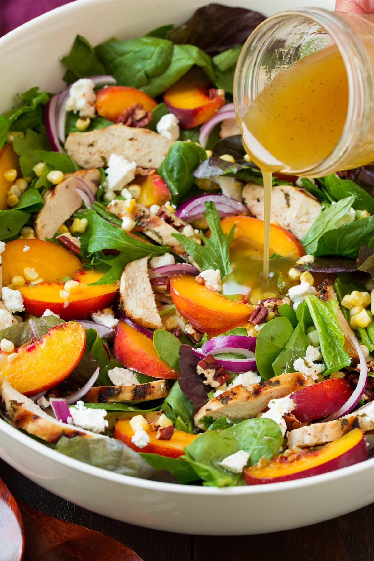 Pouring dressing over peach salad.