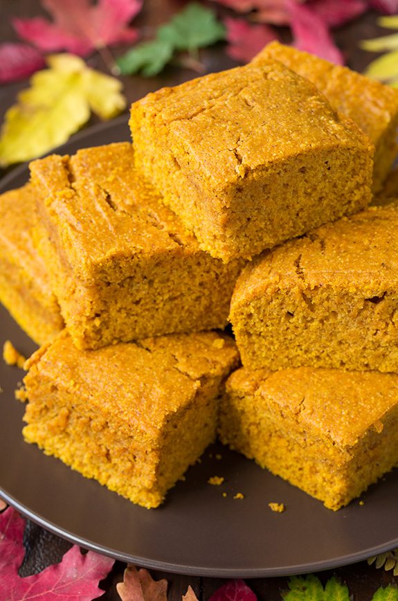 Close up image of Pumpkin Cornbread slices staked on a dark brown plate.