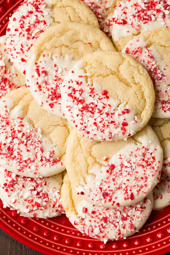Sugar cookies flavored with peppermint, dipped in white chocolate and covered with crushed candy canes. Cookies are shown served on a red plate.