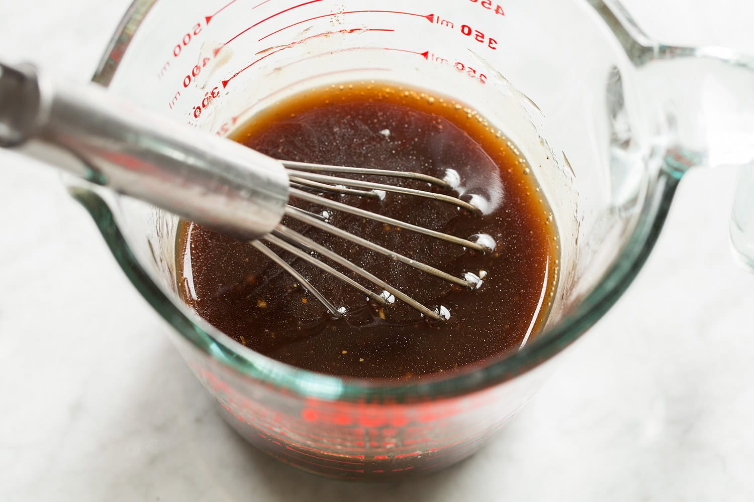 Caprese Chopped Salad Balsamic vinaigrette shown after mixing in a glass measuring cup with a whisk.