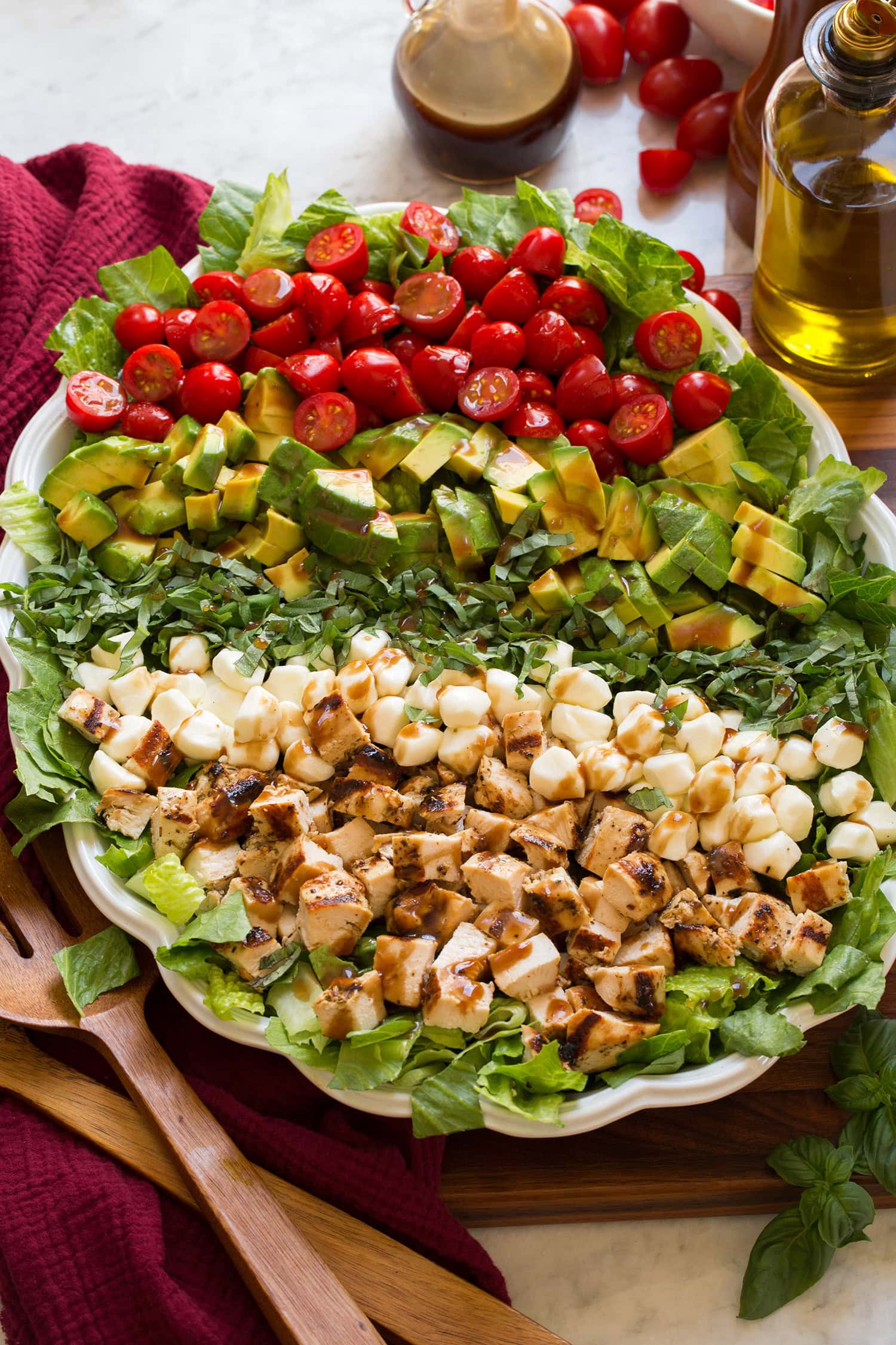 Caprese Chopped Salad Caprese chopped salad shown with salad ingredients layered together in horizontal sections before tossing. Salad is in a white scalloped oval dish.