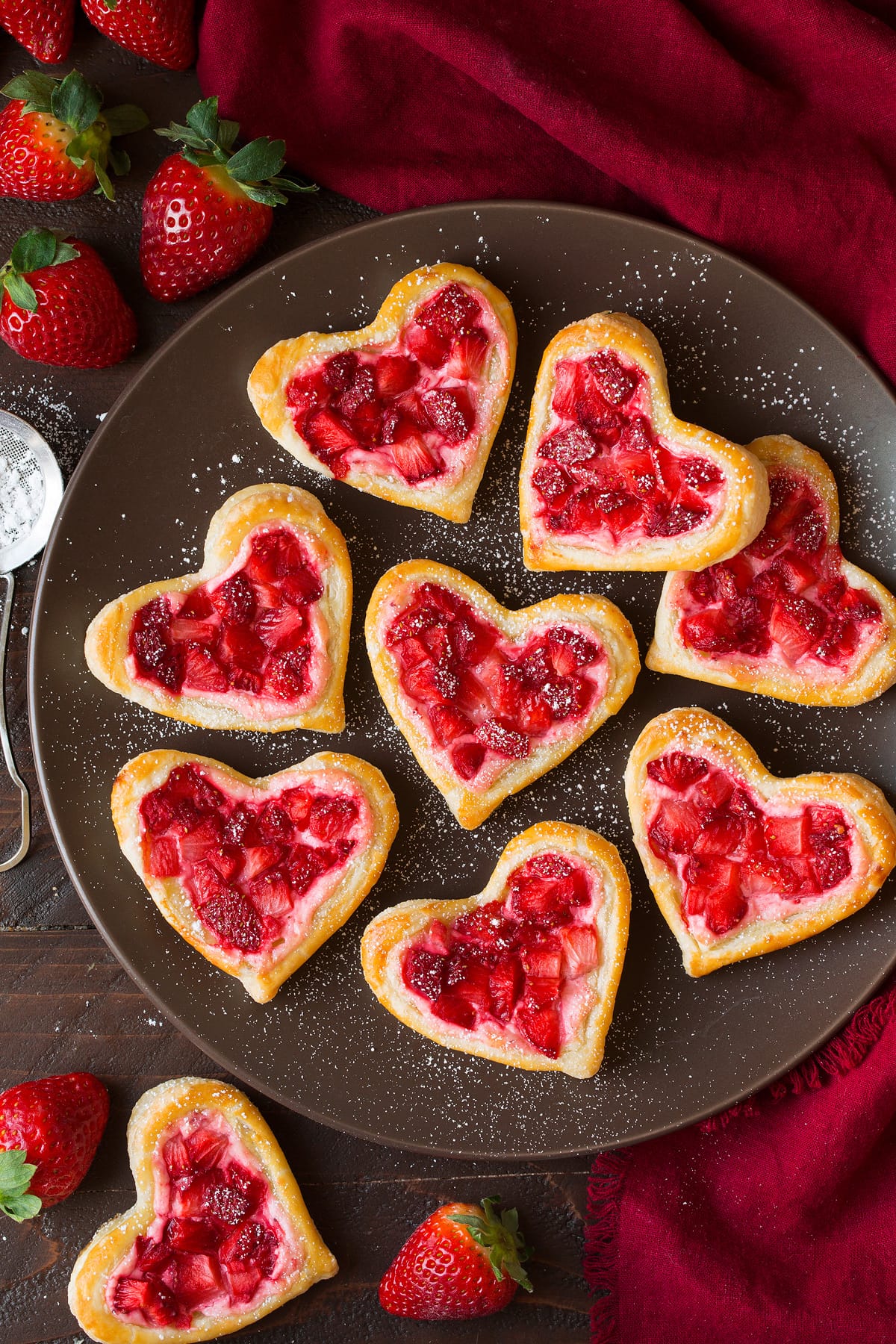 Breakfast Pastries cut into heart shapes, topped with sweetened cream cheese and strawberries.