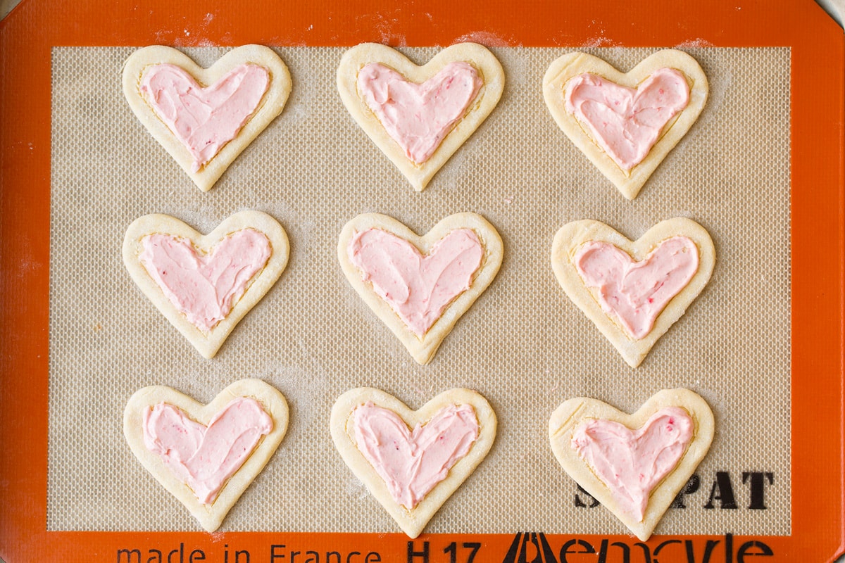 Adding cream cheese to breakfast pastries.
