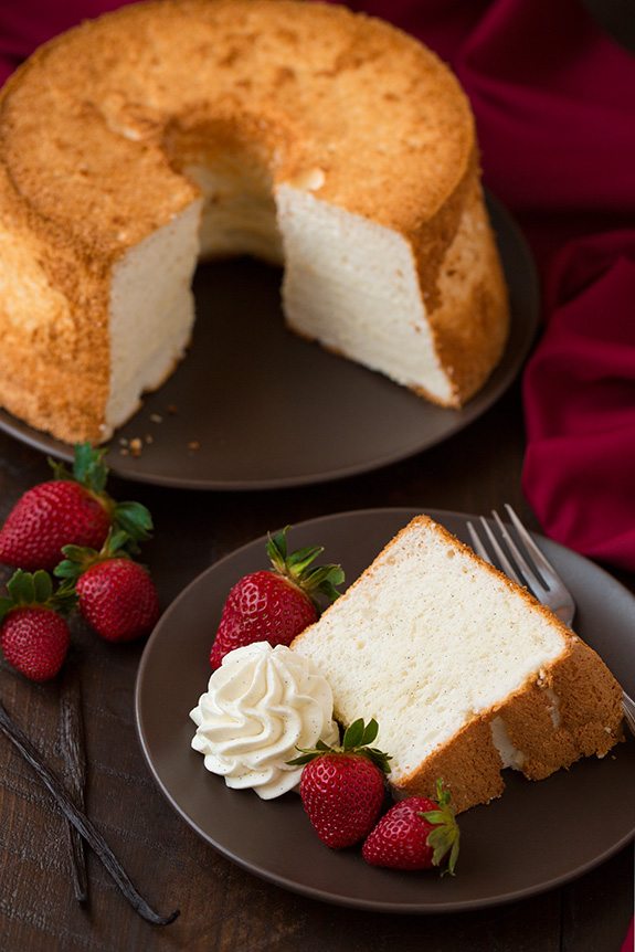 Vanilla Bean Angel Food Cake slice on plate in front of whole cake
