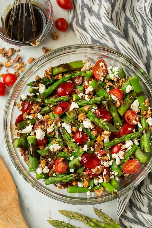Asparagus, Tomato and Feta Salad in a glass bowl with Balsamic Vinaigrette at the side