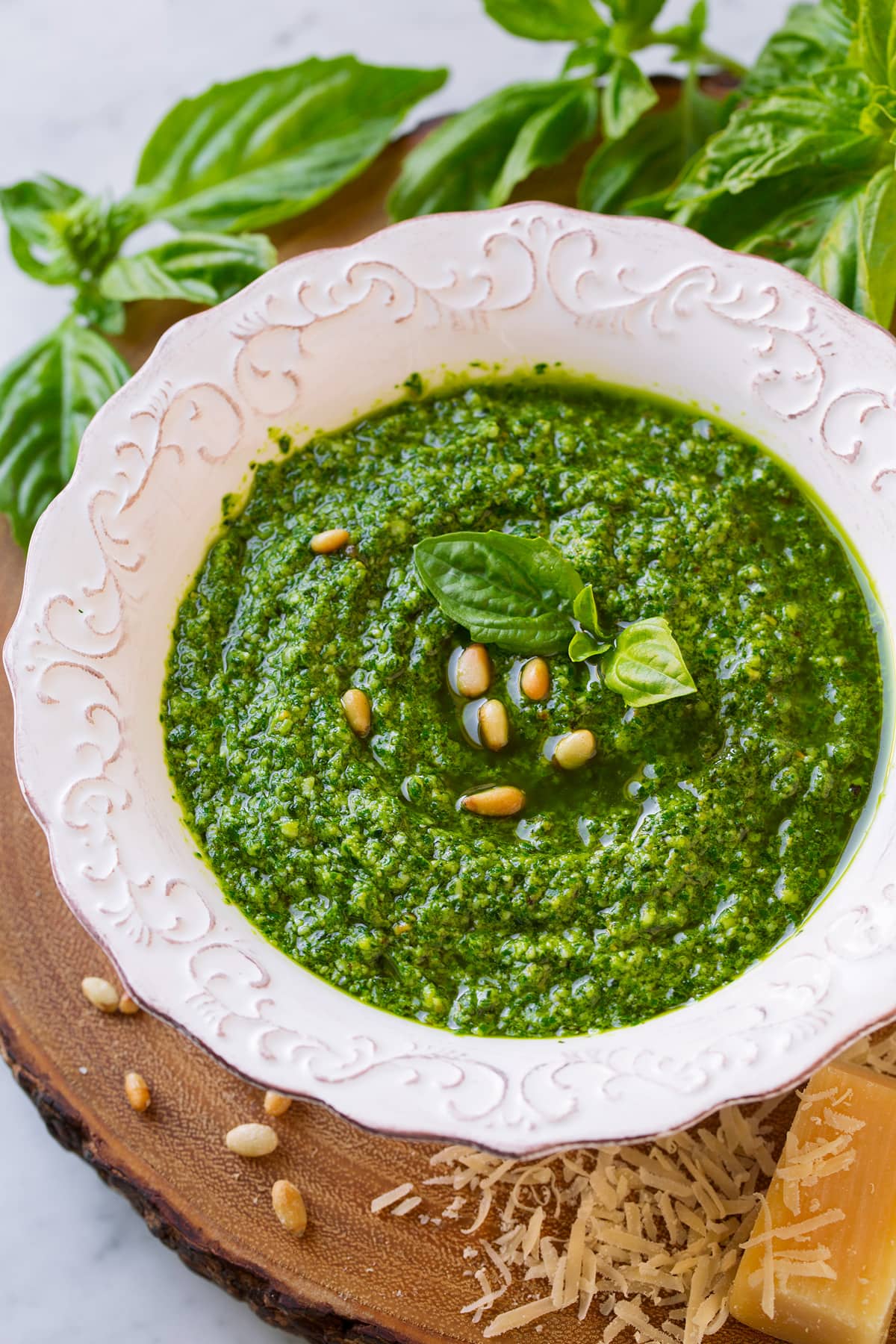 Basil pesto in a white serving bowl topped with pine nuts and basil.