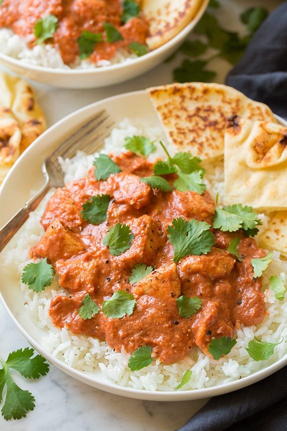 Chicken Tikka Masala shown here in a single serving in a white bowl served with basmati rice and naan.