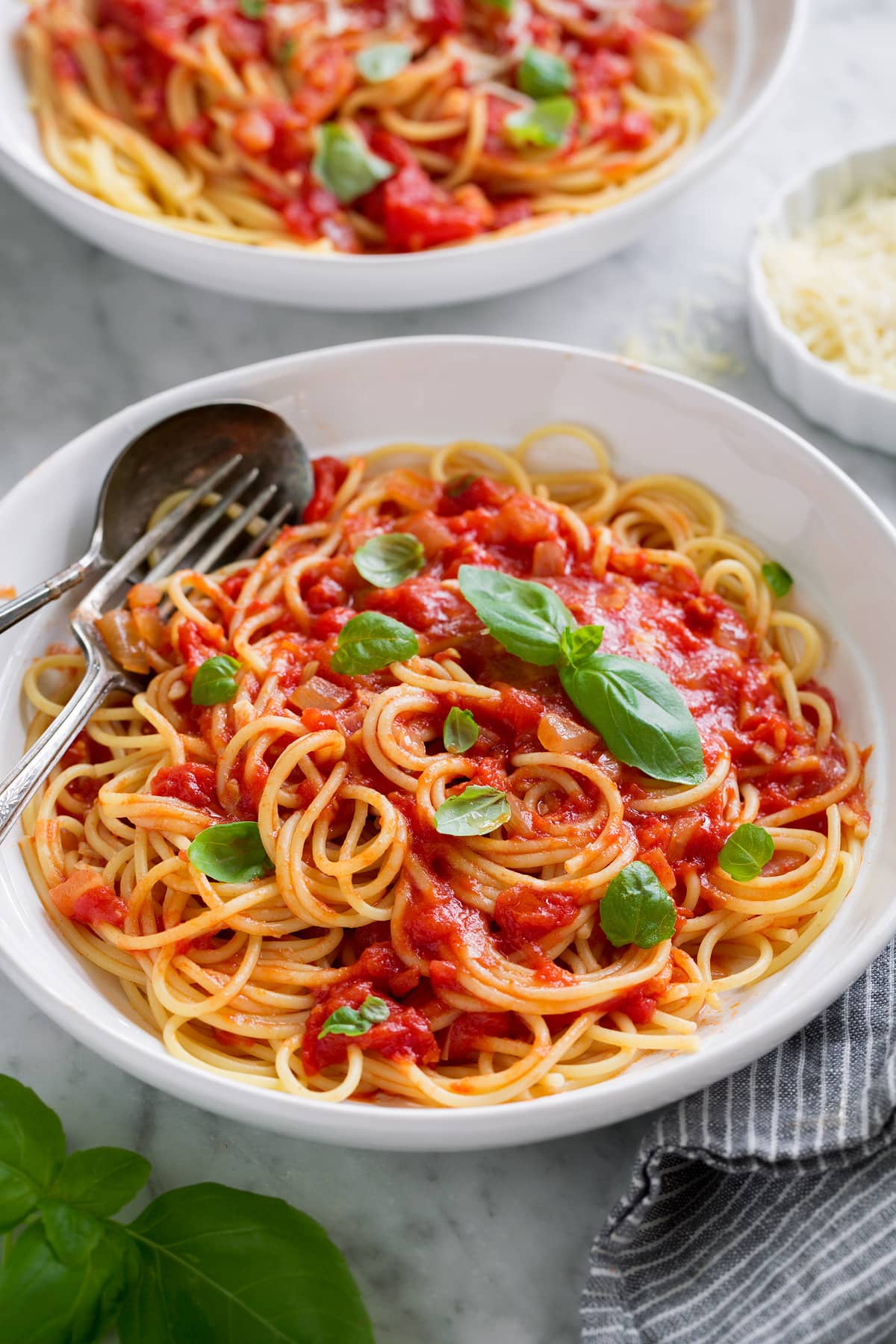 Marinara sauce served tossed with spaghetti, parmesan and fresh basil. Shown in a white pasta bowl.