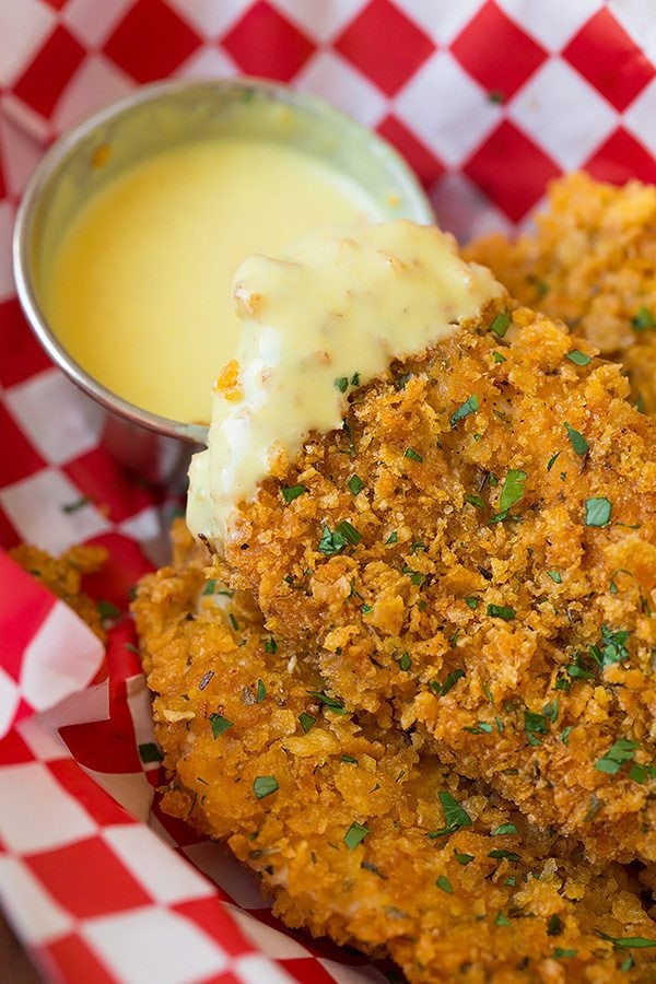 Close up image of a chicken strip dipped in honey mustard sauce.