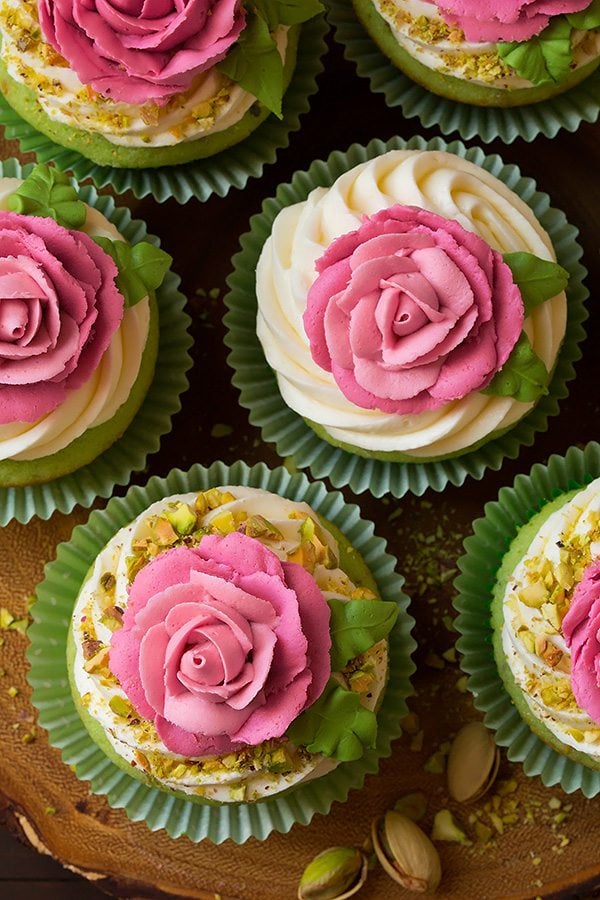 Pistachio cupcakes with pink piped buttercream roses on top.