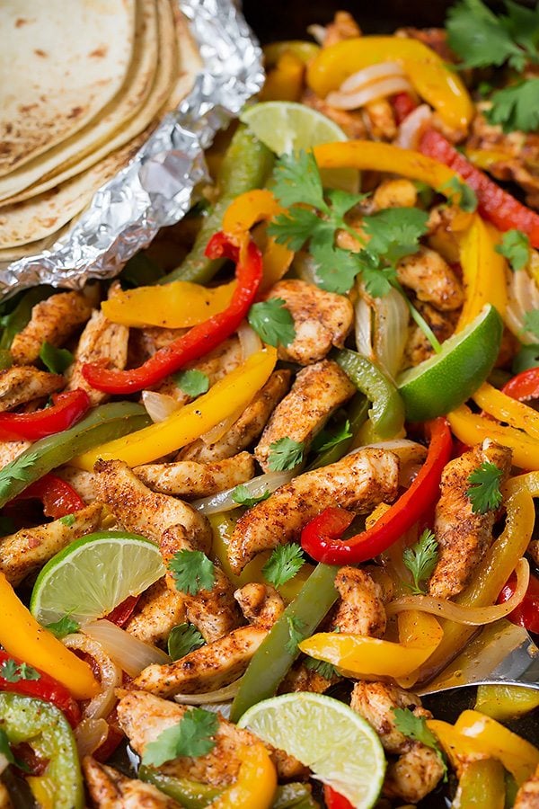 Close up image of chicken fajita mixture on a dark sheet pan.