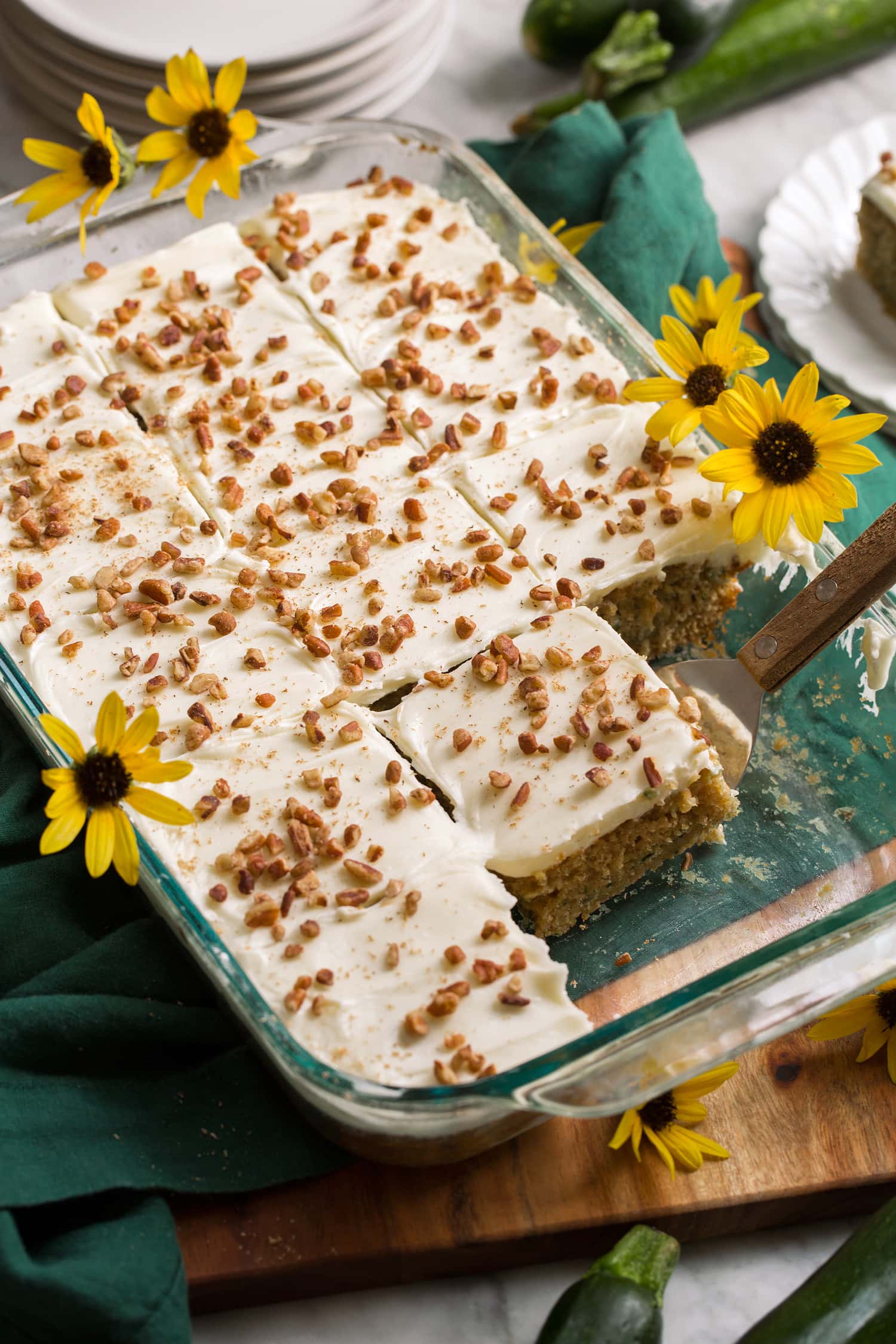 Glass baking pan with homemade zucchini cake topped with cream cheese frosting and chopped pecans. Glass baking pan with homemade zucchini cake topped with cream cheese frosting and chopped pecans.