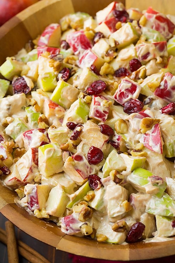 Apple fruit salad in a wooden serving bowl. It includes diced apples, cranberries, walnuts and a cinnamon cream cheese dressing.