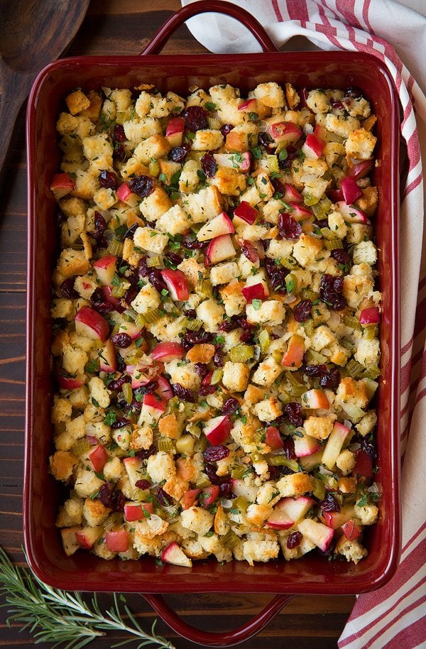 Overhead image of stuffing in a red casserole dish on a dark wooden surface.