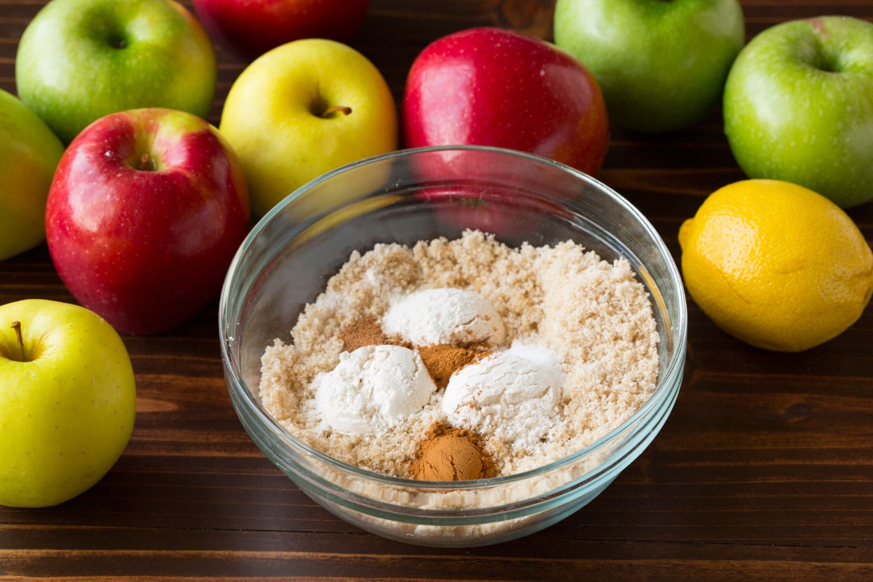 Mixing sugar and flour mixture in a small glass mixing bowl for apple pie filling.