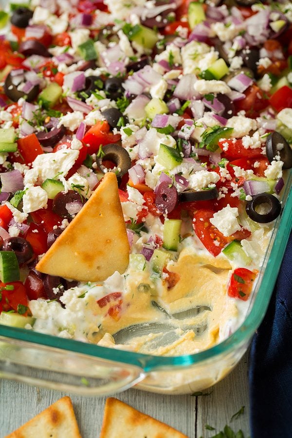 Greek Seven Layer Dip made with hummus, tomatoes, cucumbers, feta, olives and herbs.
