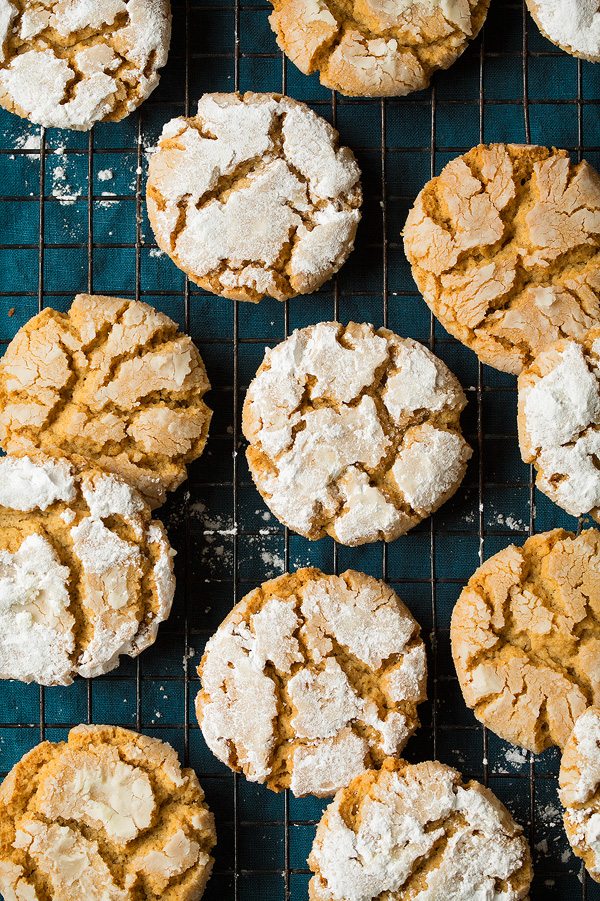 Peanut Butter Christmas Cookies. Tan peanut butter cookies are covered with powdered sugar and set on a black cooling rack over a blue cloth.