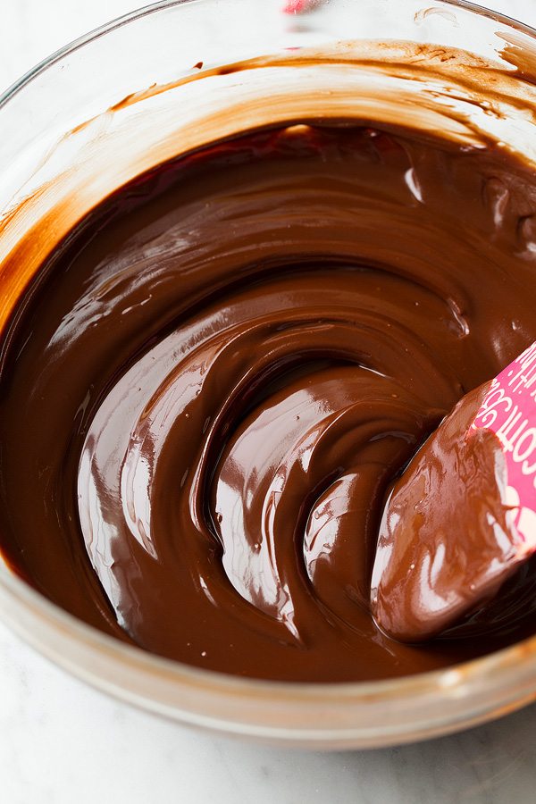 Melted chocolate in a glass mixing bowl for hot chocolate cookies.