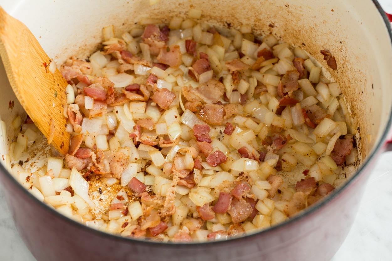 Showing how to saute bacon and onion in a large pot for zuppa toscana soup.