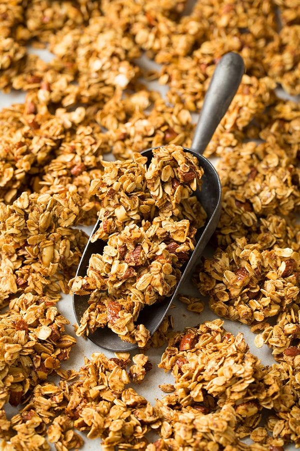 Close up image of honey almond granola in a metal scoop.