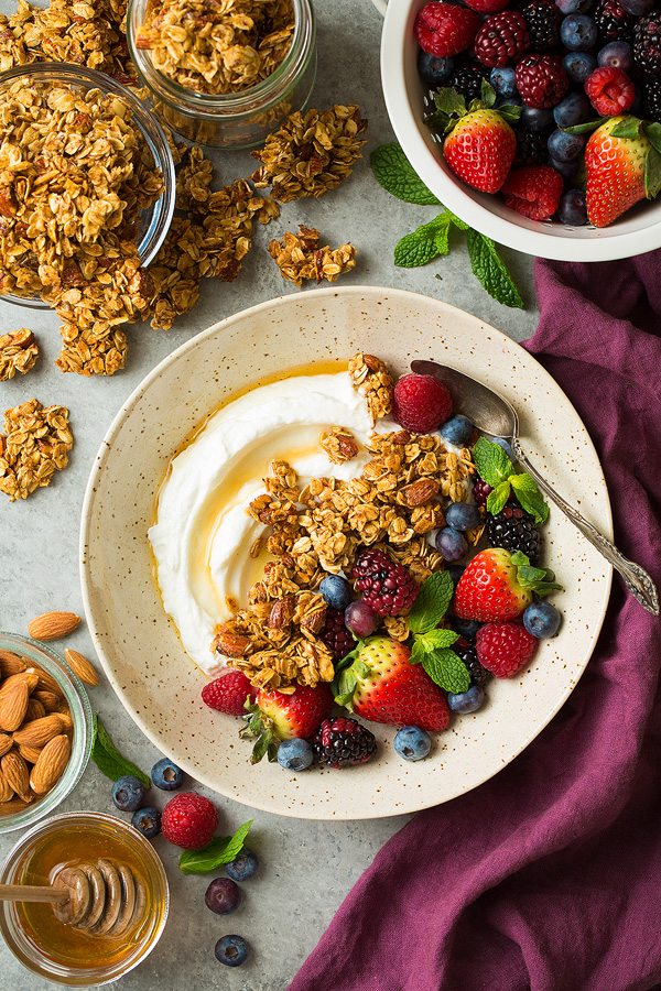 Granola in a bowl with Greek yogurt, fresh fruit and honey.