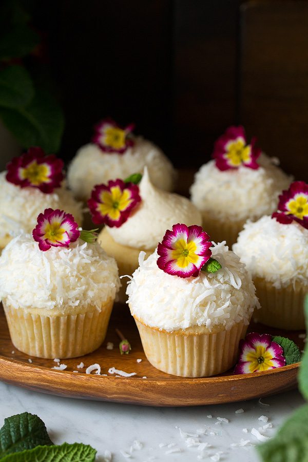 Coconut Cupcakes with coconut buttercream frosting garnished with edible flowers