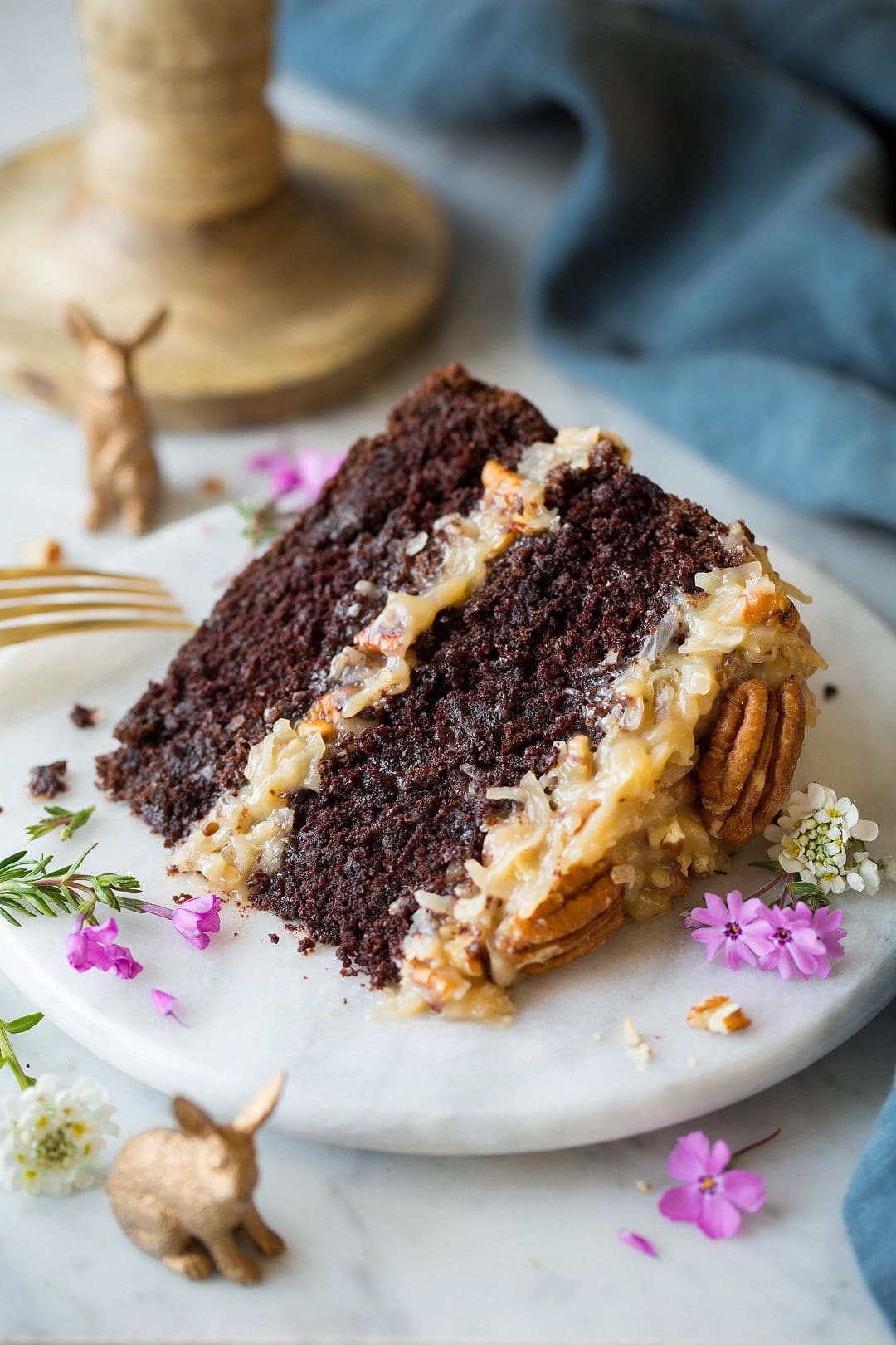 Slice of German Chocolate Cake on a marble plate set over a marble surface.