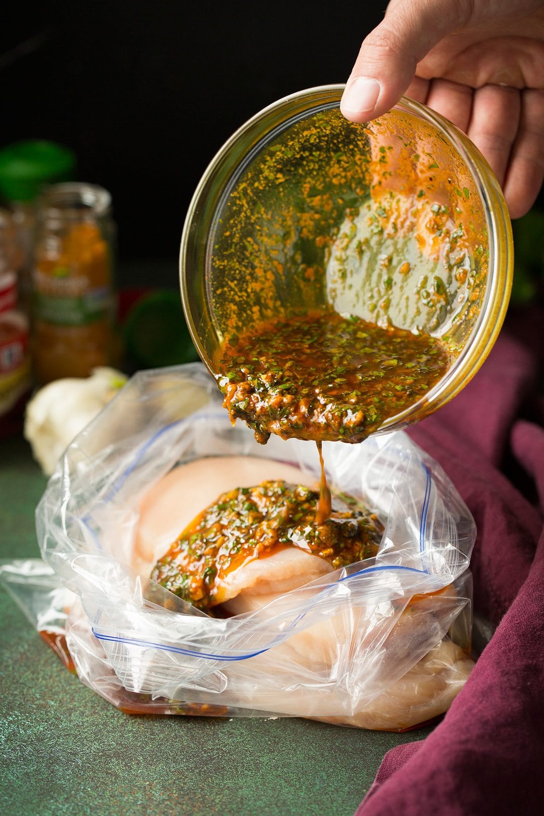 Pouring marinade over chicken breasts in a large resealable bag.