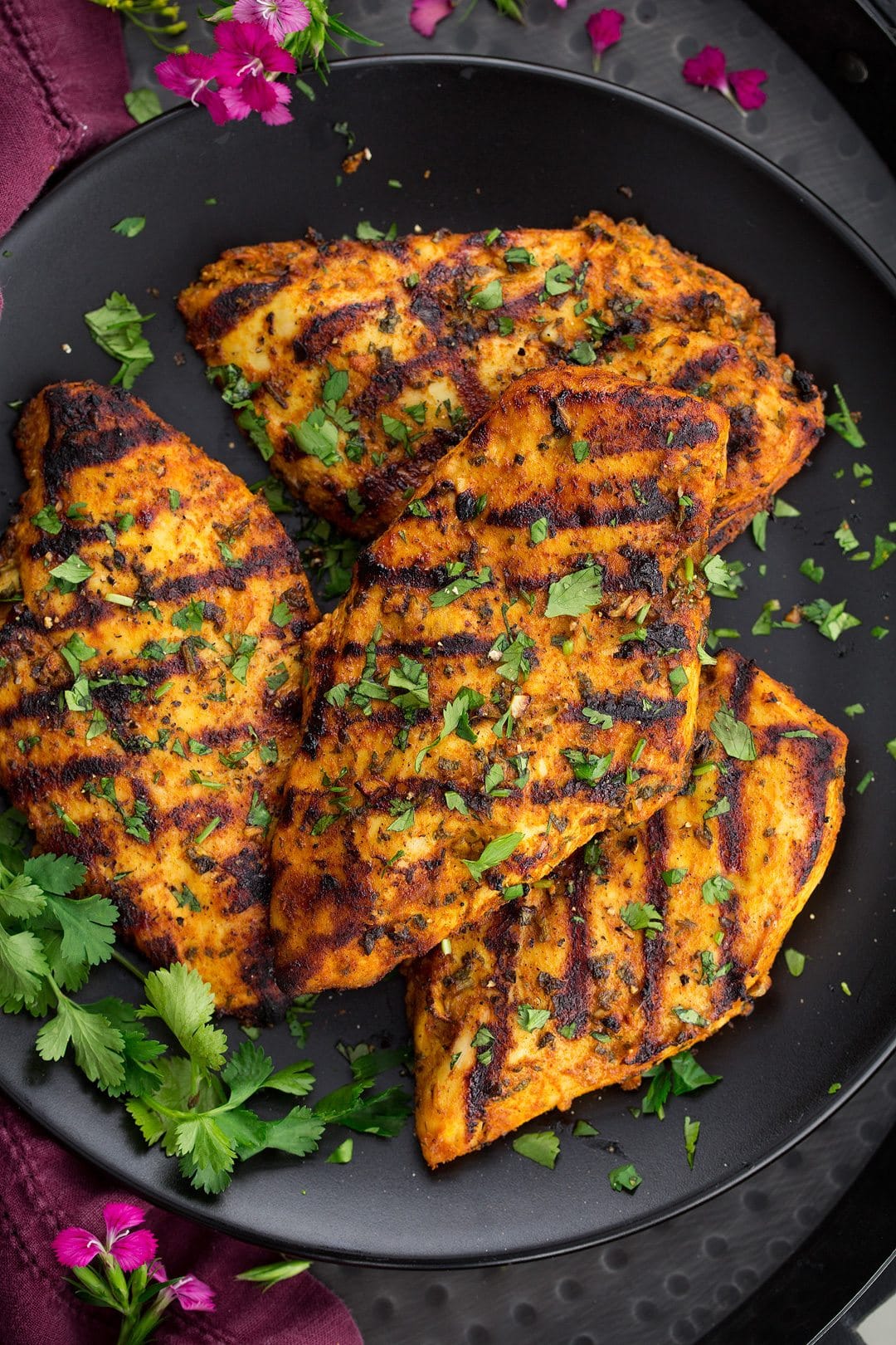 Grilled Moroccan Chicken on a dark plate with fresh parsley