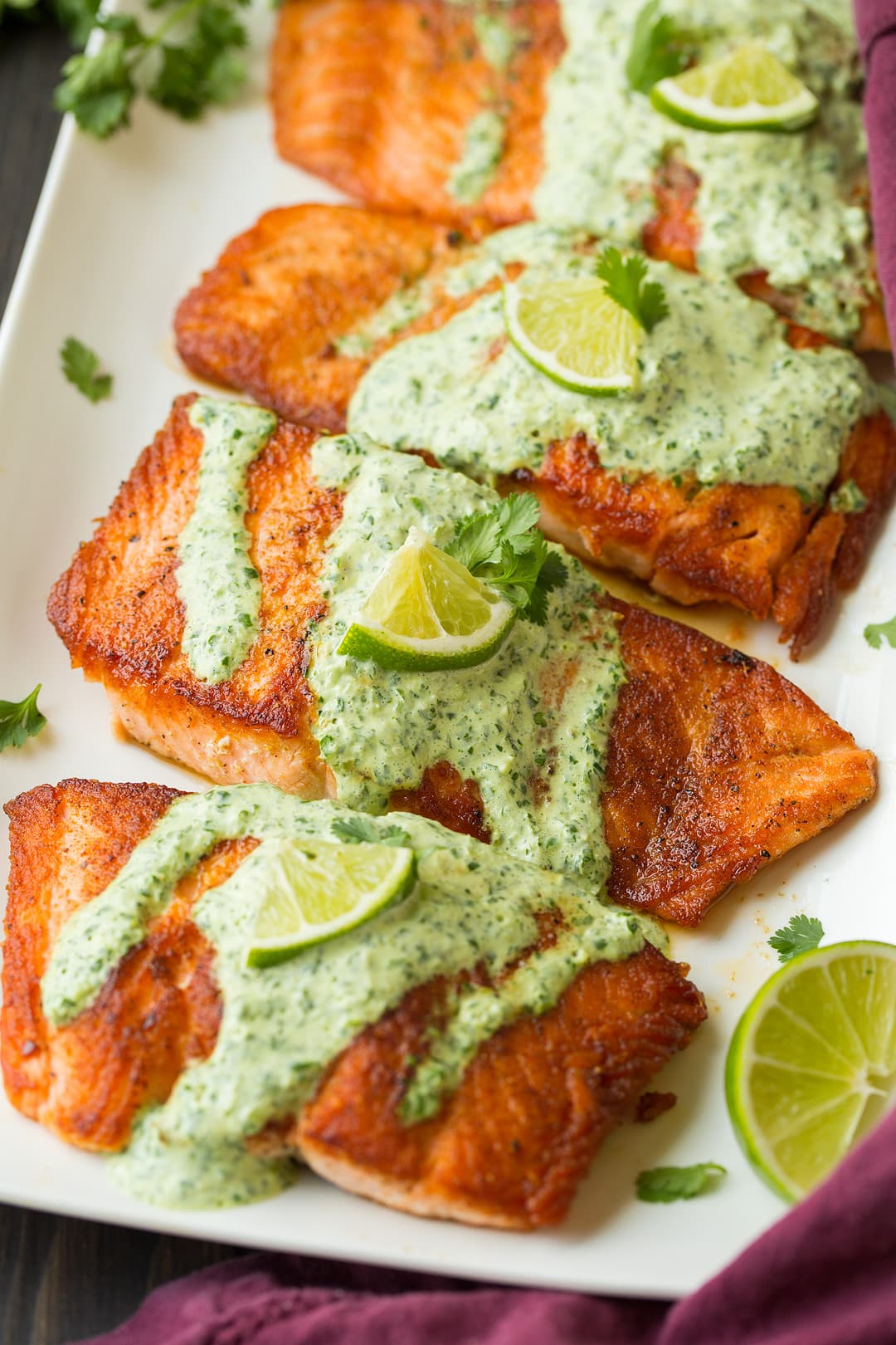 four cilantro lime salmon fillets on white platter
