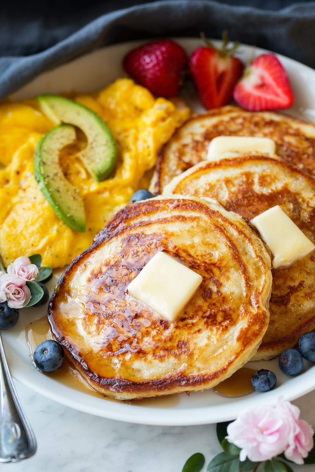 Close up image of buttermilk pancakes with perfect golden brown edges, maple syrup and butter.