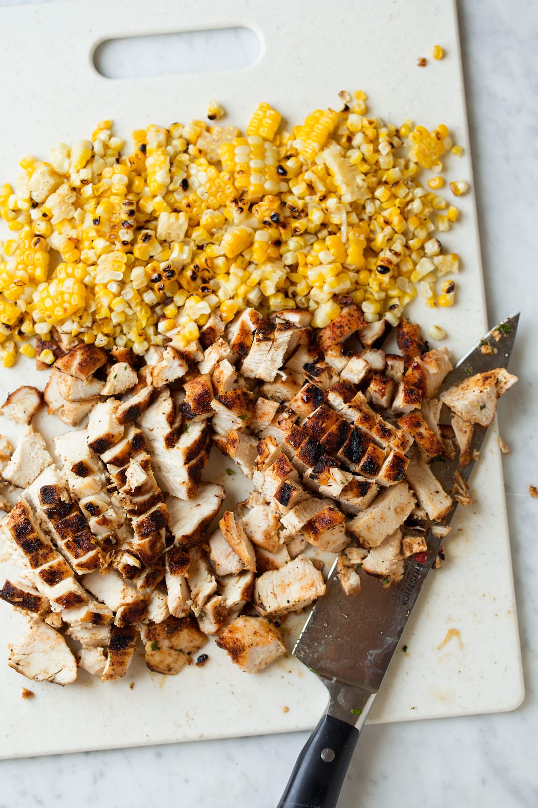 Traditional tortilla soup gets an upgrade with grilled chicken, grilled corn and plenty of diced avocados! Such a delicious summer soup! | Chicken Soup | Tortilla Soup | #cookingclassy #soup #chicken #comfortfood Ingredients for Grilled Chicken Tortilla Soup chopped up on a chopping board