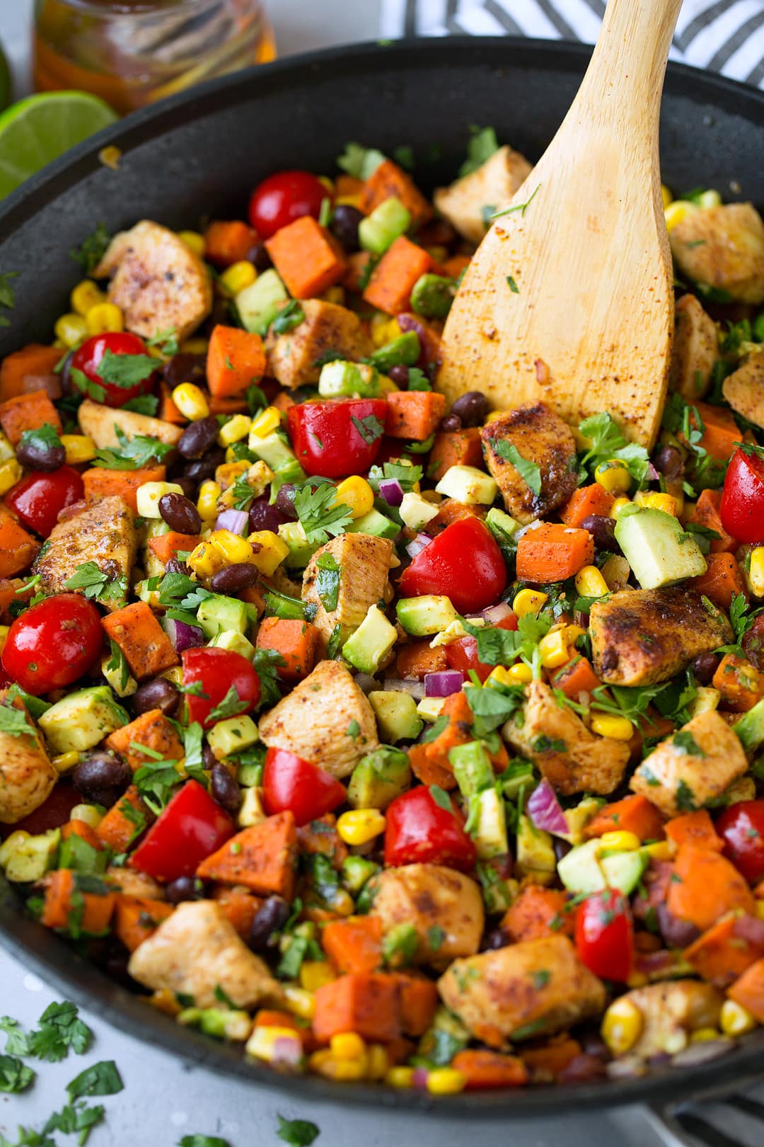 Mexican recipe of chicken, veggies and black beans with cilantro lime flavors. Shown here in a large black skillet.