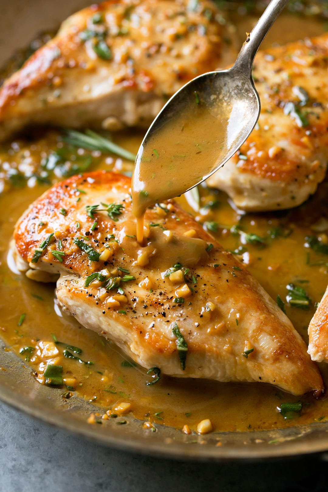 A butter sauce getting poured of Skillet Chicken with a spoon