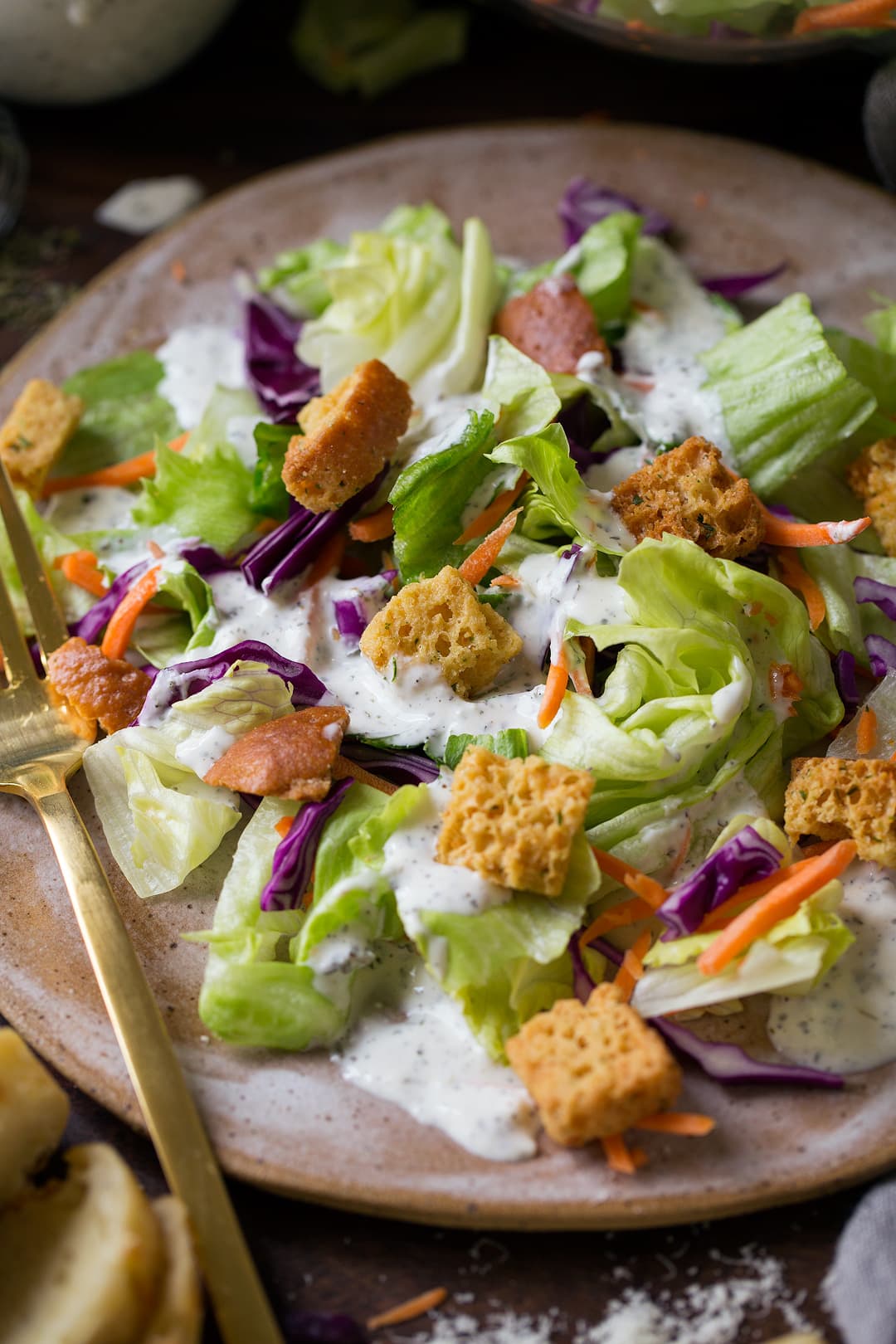 Creamy Pesto Salad Dressing over green salad on plate.