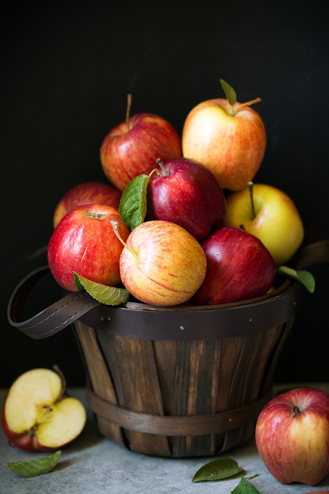 Stack of multi-colored apples in wooden bucket.