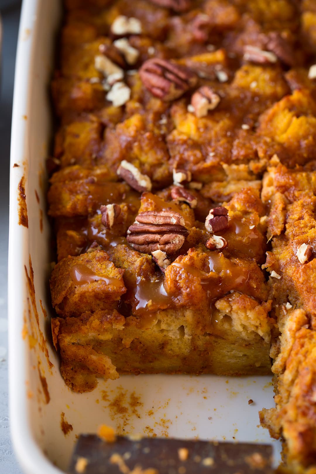 Bread Pudding in baking dish with pumpkin, spices, caramel sauce and pecans.