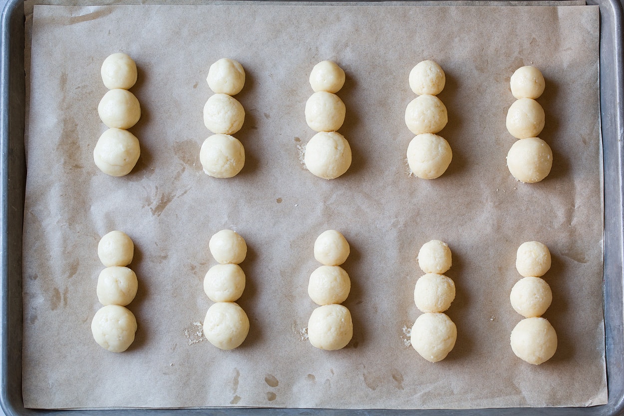 Sugar Cookies shaped into rounds of descending size in stacks of three on baking sheet to make snowman sugar cookies.