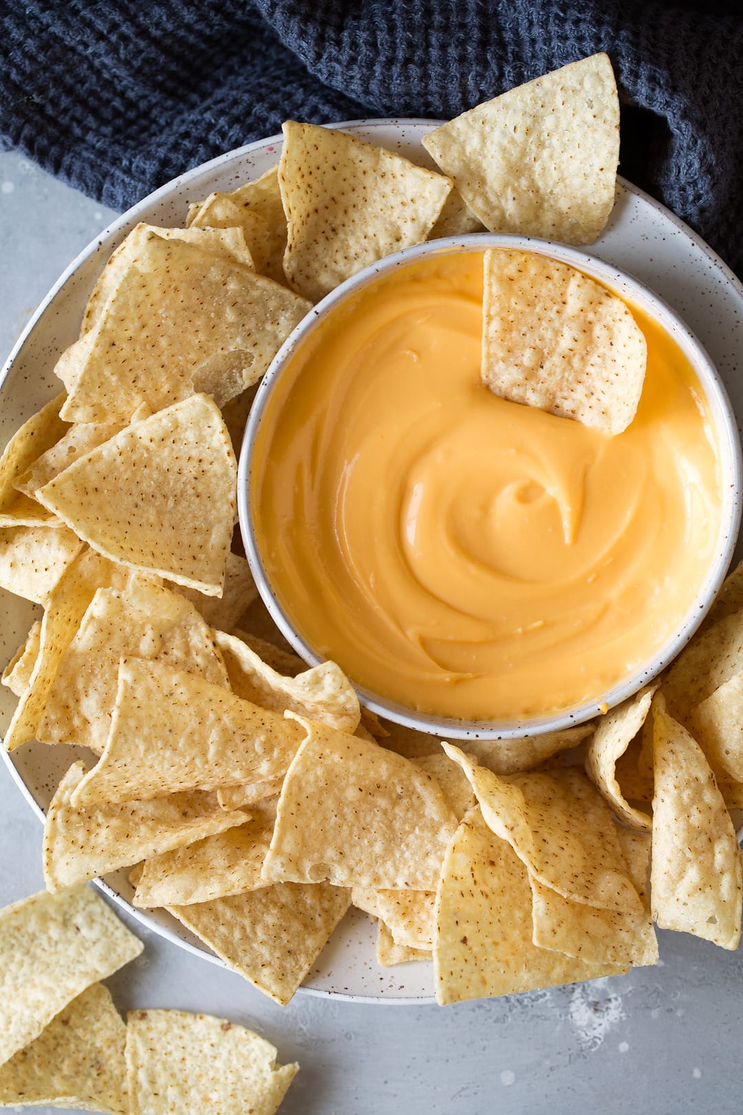 bowl of cheddar cheese dip on a plate with tortilla chips