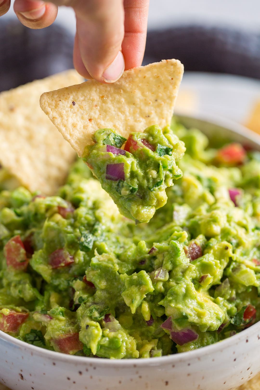 dipping a tortilla chip into fresh guacamole dip