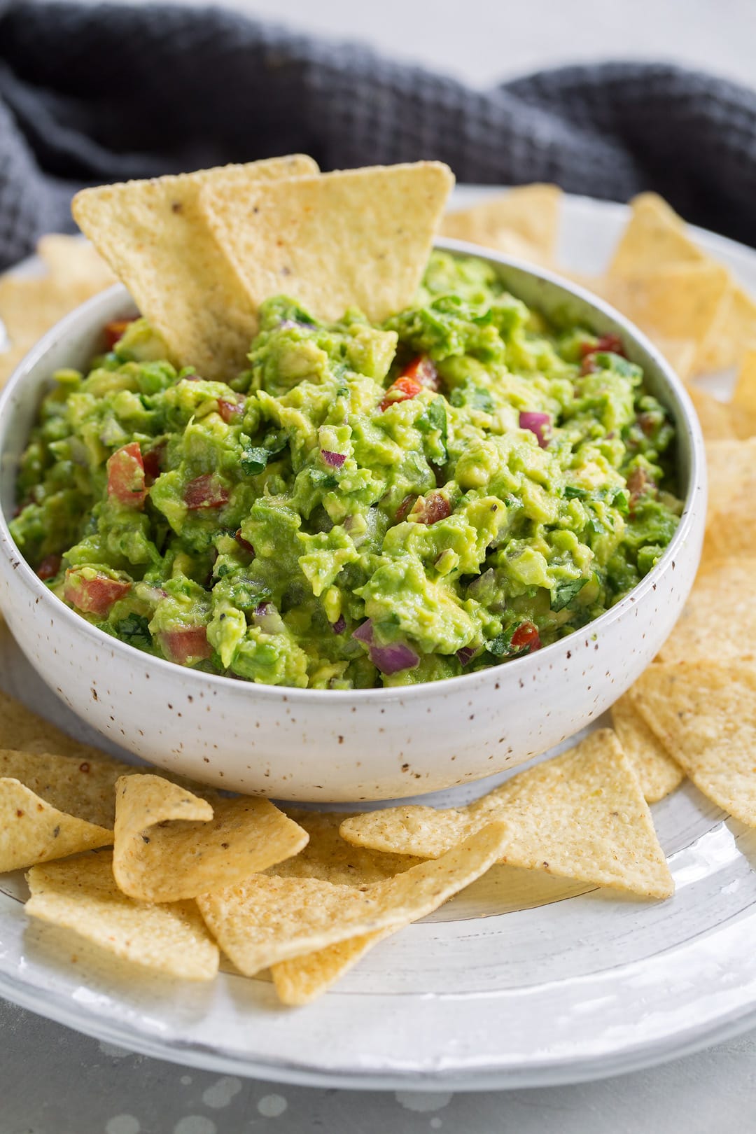 Fresh guacamole in a serving bowl with a side of chips.