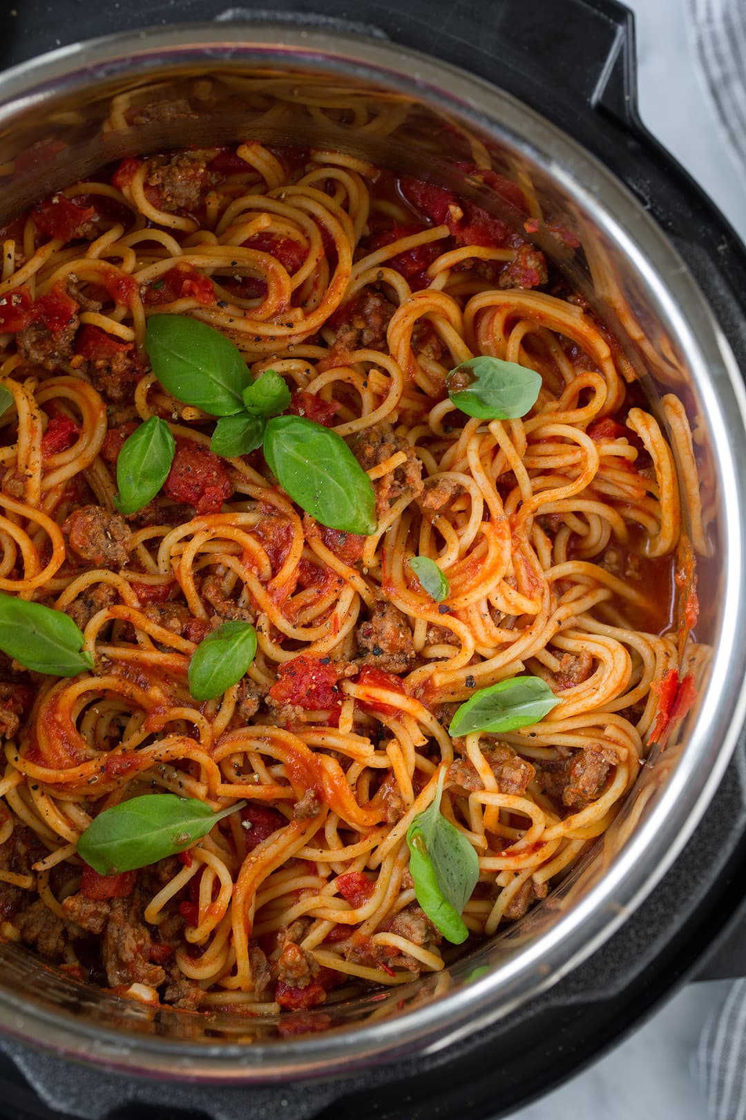 Instant Pot Spaghetti shown here after cooking in the instant pot garnished with fresh basil