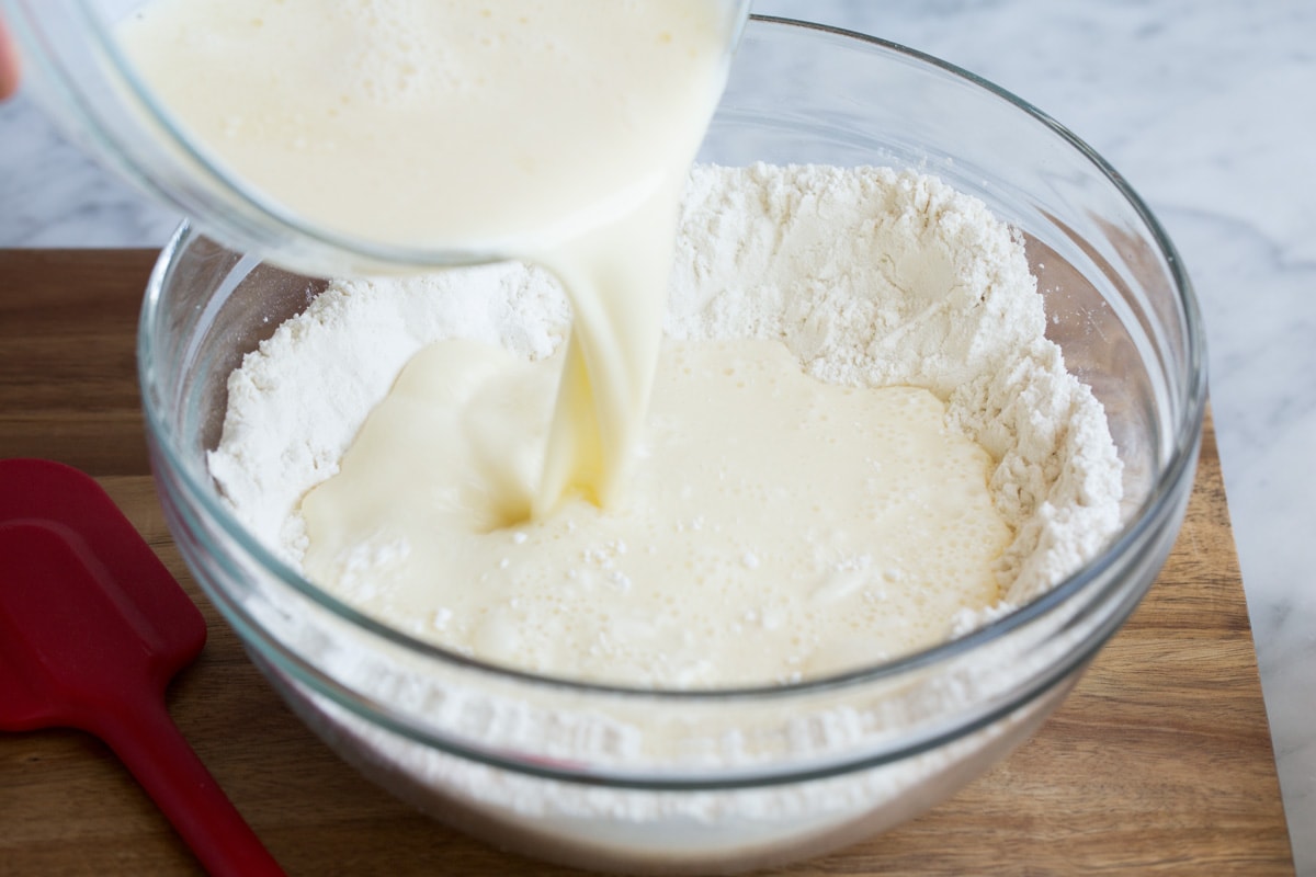 Pouring wet mixture into well in center of dry mixture in mixing bowl.