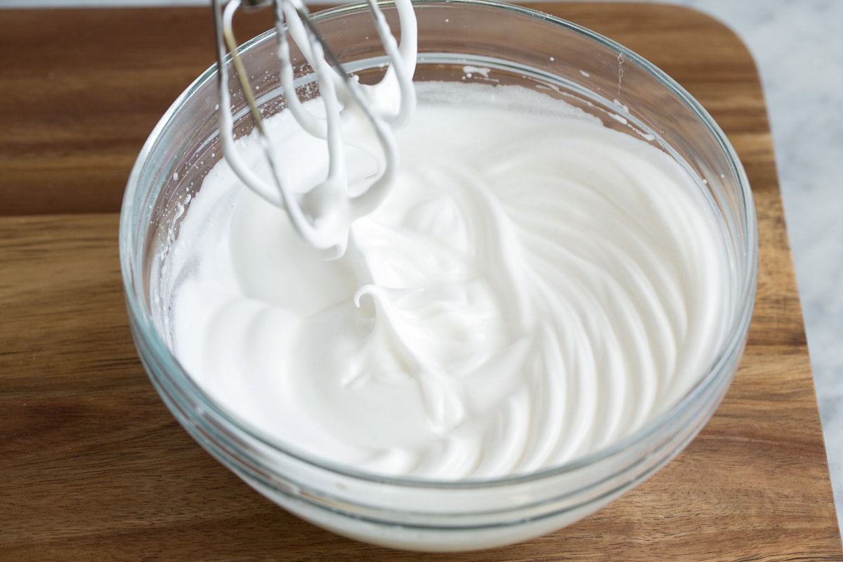 Whipping egg whites in a glass mixing bowl to medium stiff peaks.