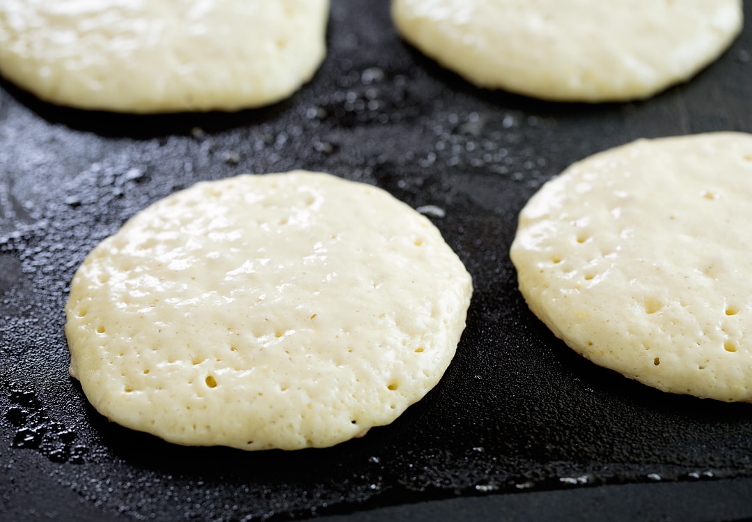 pancakes being cooked on a electric griddle