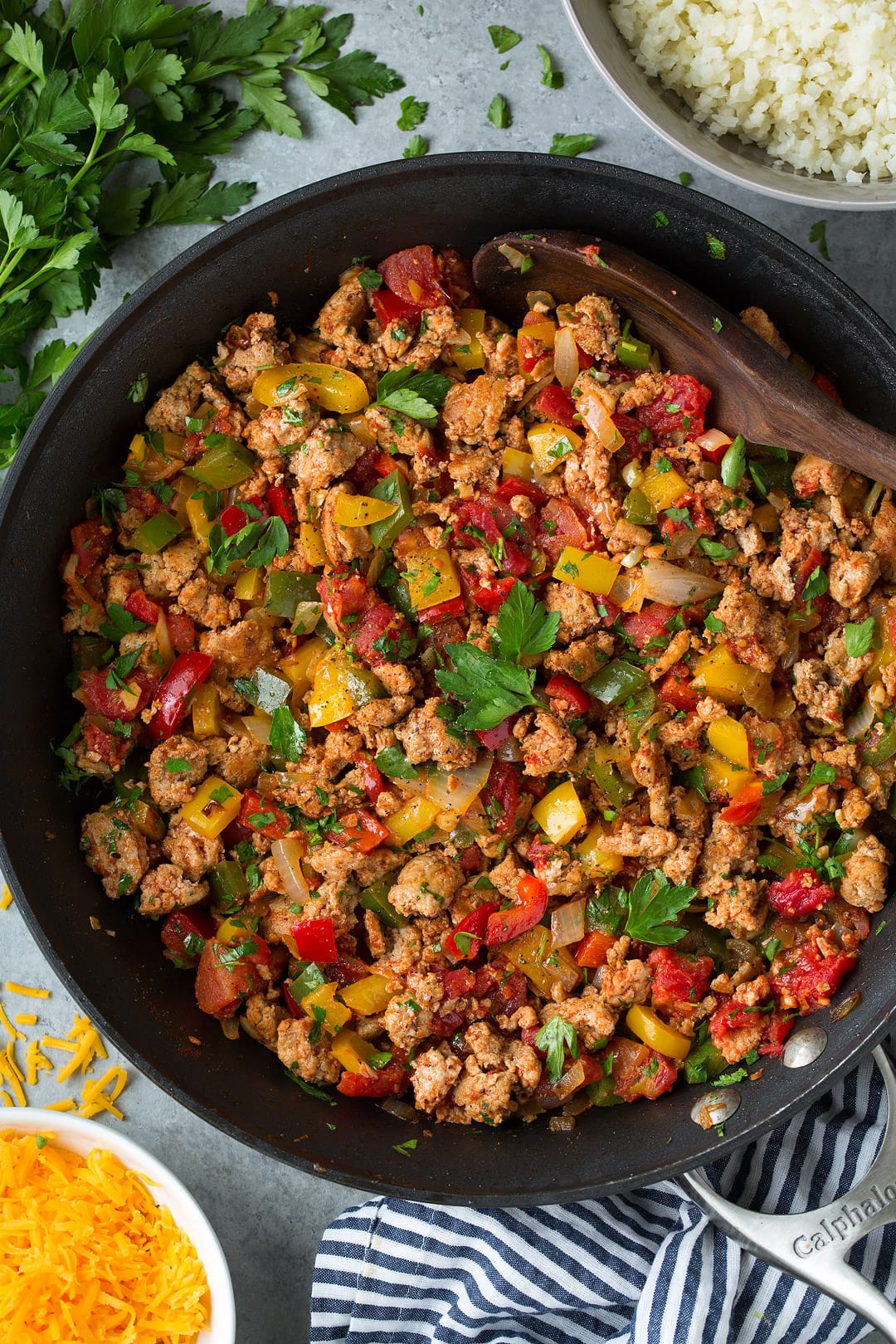 Unstuffed Pepper mixture of ground turkey, peppers and parsley shown here in a dark skillet on a grey surface