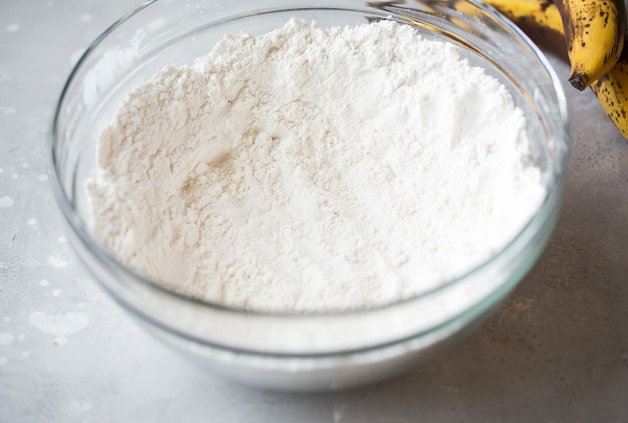 This is the best banana bread recipe! Quick and easy to make and no mixer is required. It's perfectly moist and amazingly tender and it's brimming with banana flavor. Simply put, everyone will have a hard time stopping at just one slice! #cookingclassy #banana #bread #bananabread whisk dry ingredients for banana bread in a glass bowl