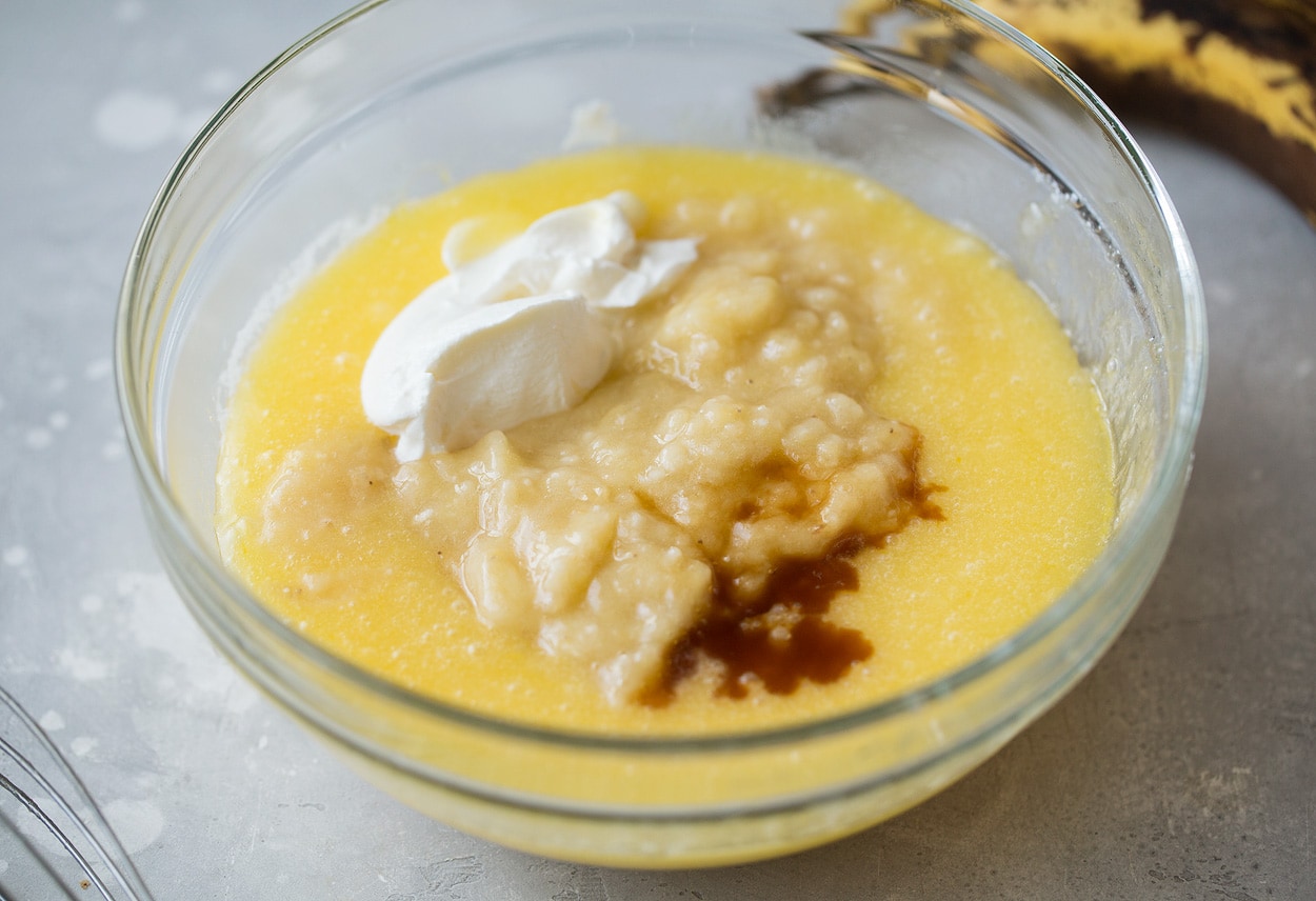 This is the best banana bread recipe! Quick and easy to make and no mixer is required. It's perfectly moist and amazingly tender and it's brimming with banana flavor. Simply put, everyone will have a hard time stopping at just one slice! #cookingclassy #banana #bread #bananabread bananas vanilla and sour cream for banana bread in a bowl